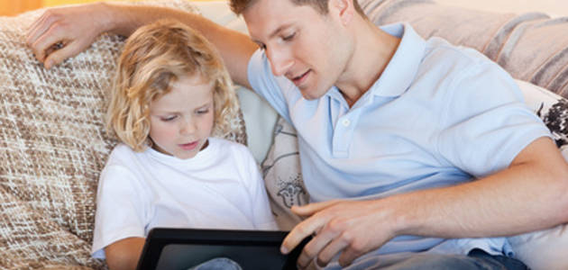 Father and son using tablet on the sofa together