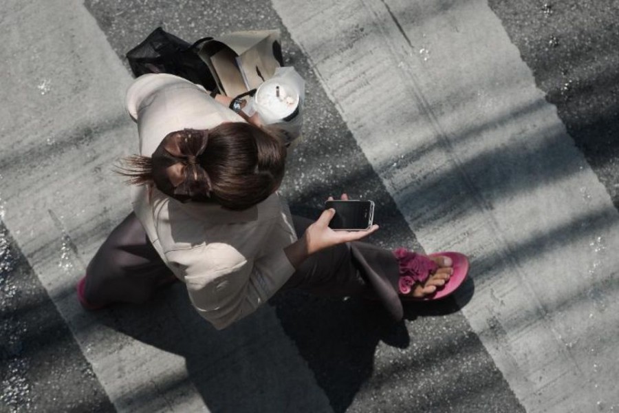 Une femme consulte son smartphone dans la rue